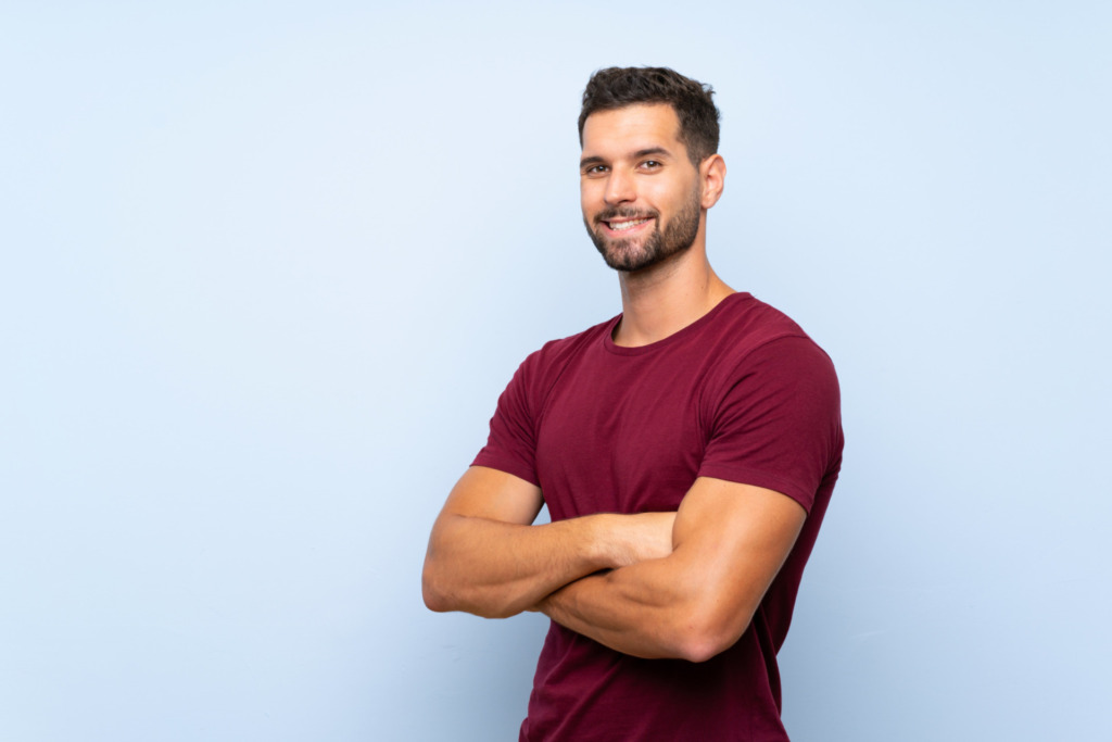 Handsome man over isolated blue background with arms crossed and looking forward